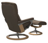 Rückansicht eines braunen Einzelsessels mit passendem Hocker, beide mit Holz- und Metallgestell.