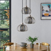 Drei moderne Hängeleuchten in einem Esszimmer, aus der Perspektive von schräg unten fotografiert, mit einem runden Holztisch und Geschirr darunter.