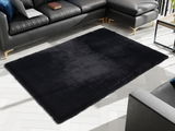 Schwarzer Fellteppich in einem modernen Wohnzimmer, umgeben von einem Ecksofa. Draufsicht auf den Teppich.