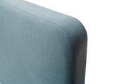 Close-up van een blauw gestoffeerd bed, gezien vanaf de zijkant