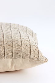 Beiges Kissen mit strukturiertem, gestricktem Muster, seitliche Perspektive