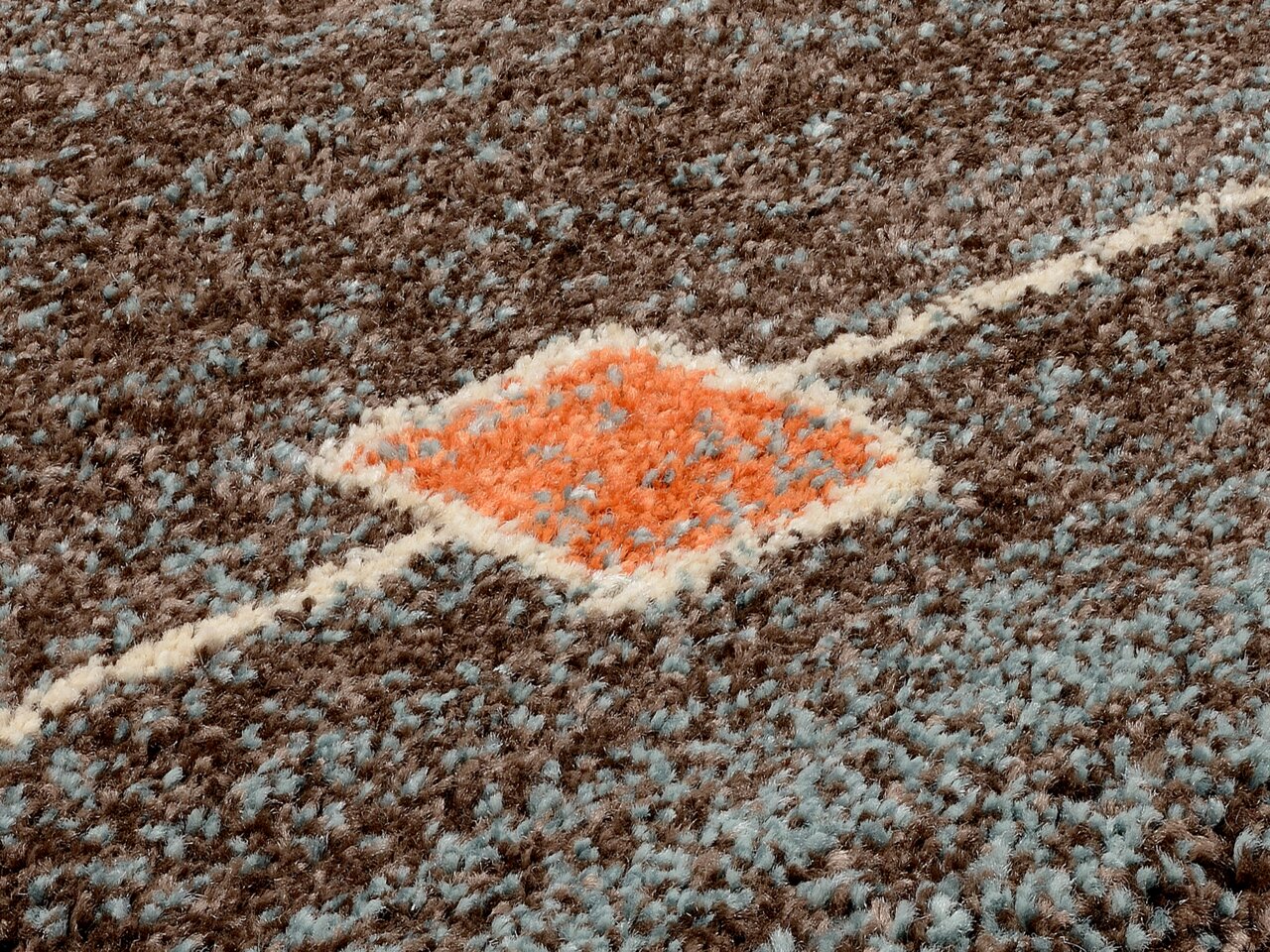 Nahaufnahme eines Frisé-Teppichs mit braunen, blauen und orangefarbenen Mustern in diagonaler Perspektive.