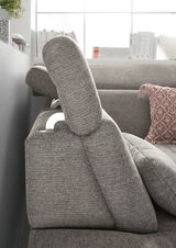 Seitenansicht einer grauen Rundecke mit verstellbarer Kopfstütze und dekorativem Kissen im Hintergrund.