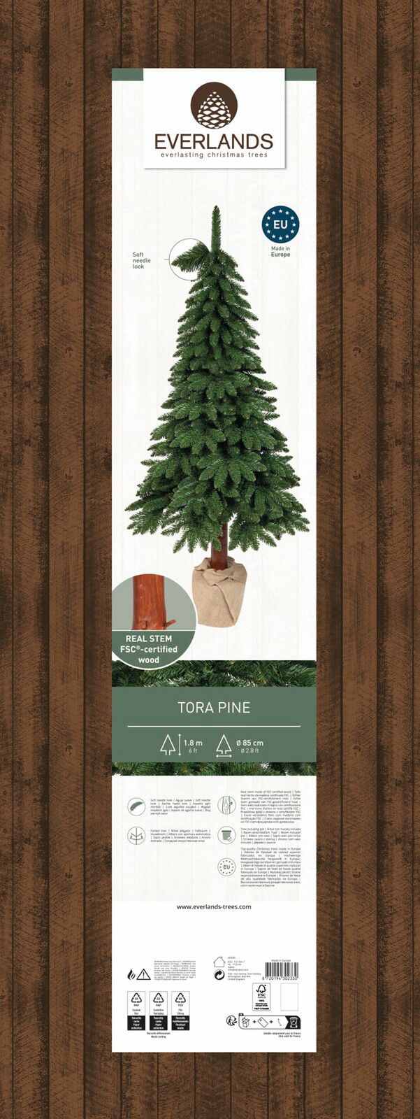 Künstlicher Weihnachtsbaum Tora Kiefer, 1,8 m hoch, mit weichen Nadeln und echtem FSC-zertifiziertem Holzstamm, in einem Jutesack präsentiert, Frontalansicht.