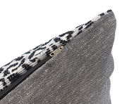 Nahaufnahme einer Kissenhülle mit Reißverschluss, schwarz-weißes Muster und grauer Stoff, seitliche Perspektive
