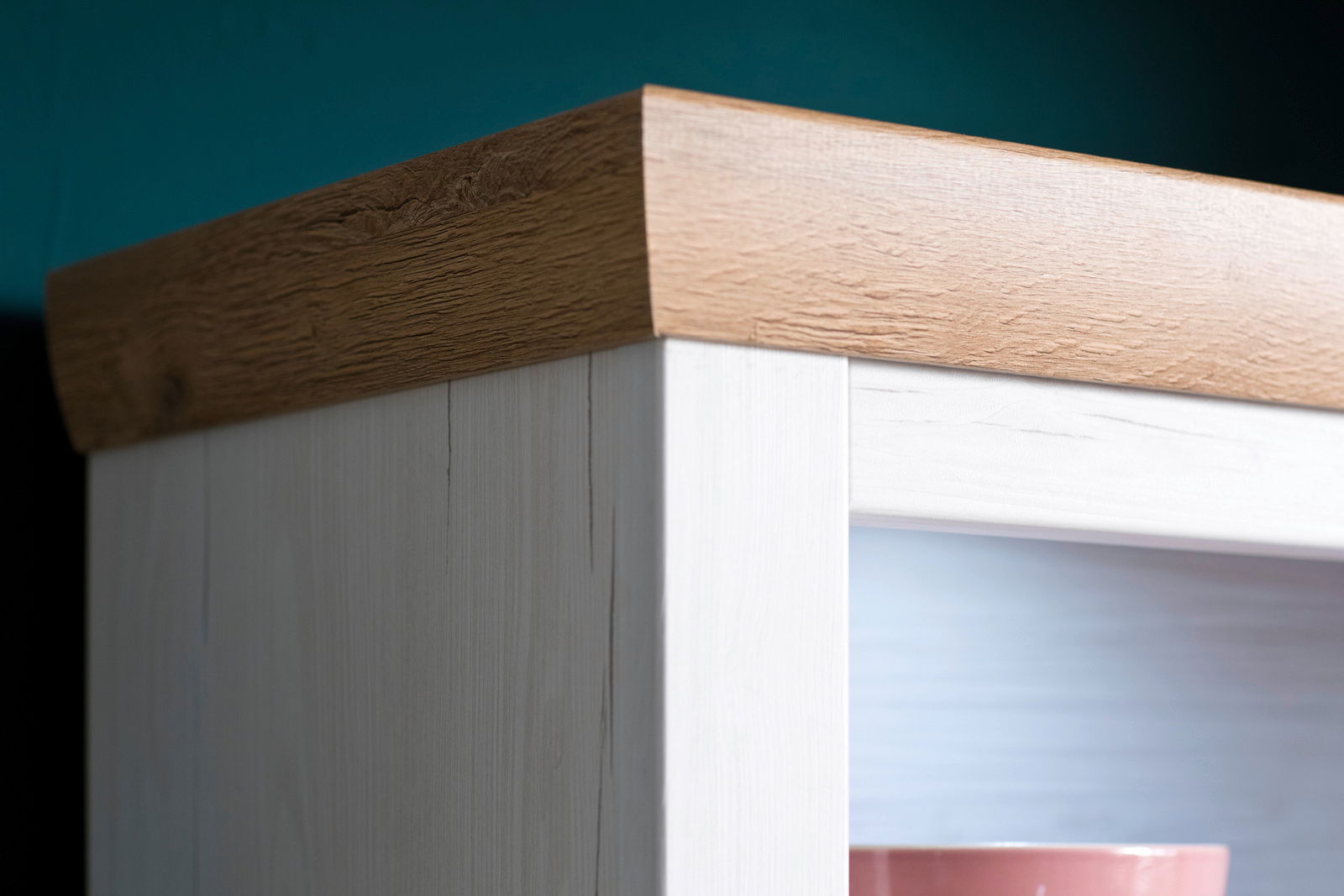 Nahaufnahme einer Holzmöbelkante mit heller Holzstruktur und dunklerer Oberkante, perspektivisch von unten rechts aufgenommen.