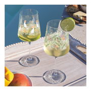 Zwei dekorative Weingläser mit tropischen Motiven, gefüllt mit einem erfrischenden Getränk und Limettenscheiben, auf einem Tablett am Pool bei Tageslicht.