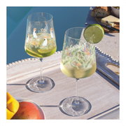 Zwei dekorative Weingläser mit tropischen Motiven, gefüllt mit einem erfrischenden Getränk und Limettenscheiben, auf einem Tablett am Pool bei Tageslicht.