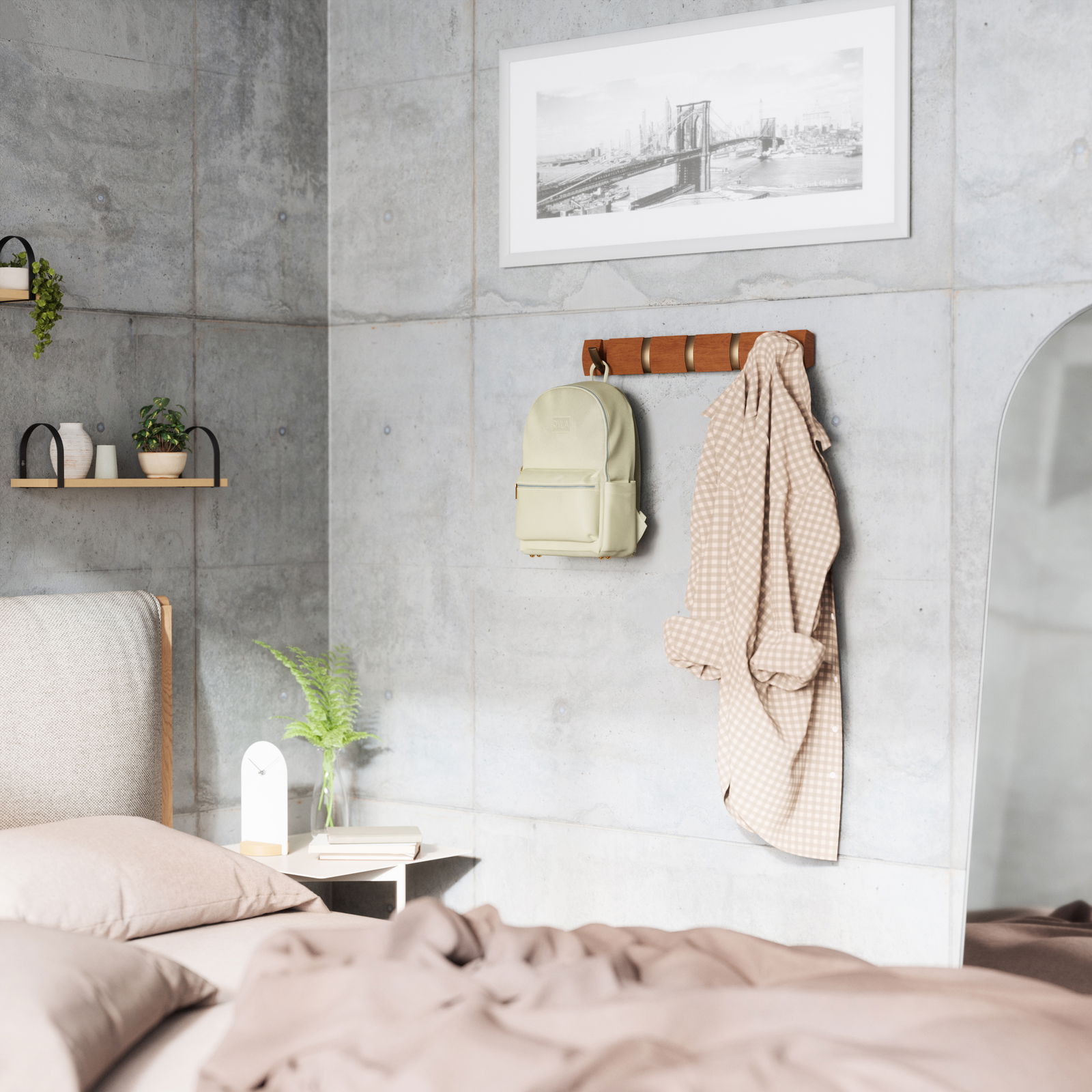 Wandgarderobe aus Holz mit mehreren Haken, an der ein beiger Rucksack und ein kariertes Hemd hängen. Perspektive: seitliche Ansicht in einem modern eingerichteten Schlafzimmer mit Betonwänden.