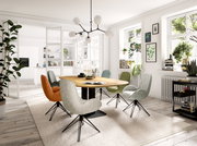 Moderner Essbereich mit rundem Holztisch und bunten Armlehnstühlen in einem hellen Raum mit großen Fenstern, Blick von der Seite.