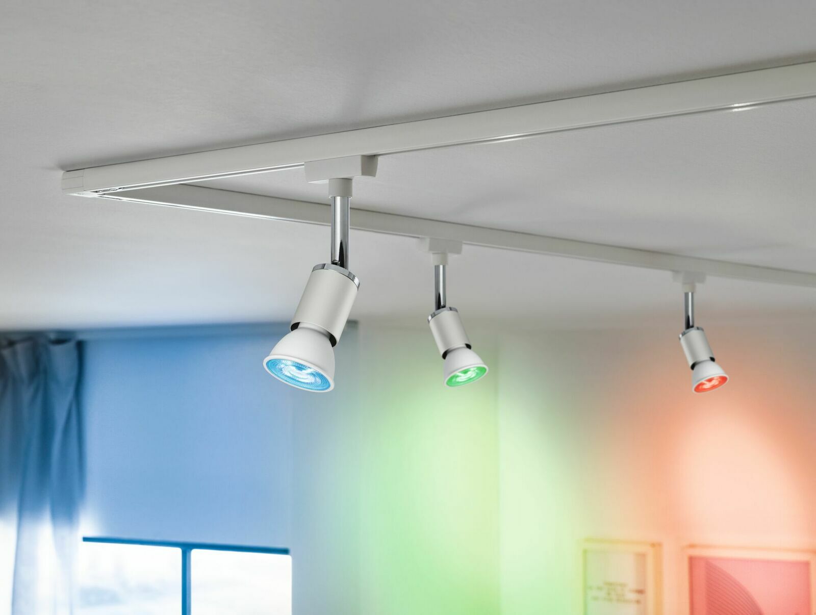 Dreifaches LED-Leuchtmittel von PAULMANN URAIL in einer Deckenmontage, mit blauer, grüner und roter Beleuchtung, seitliche Perspektive.