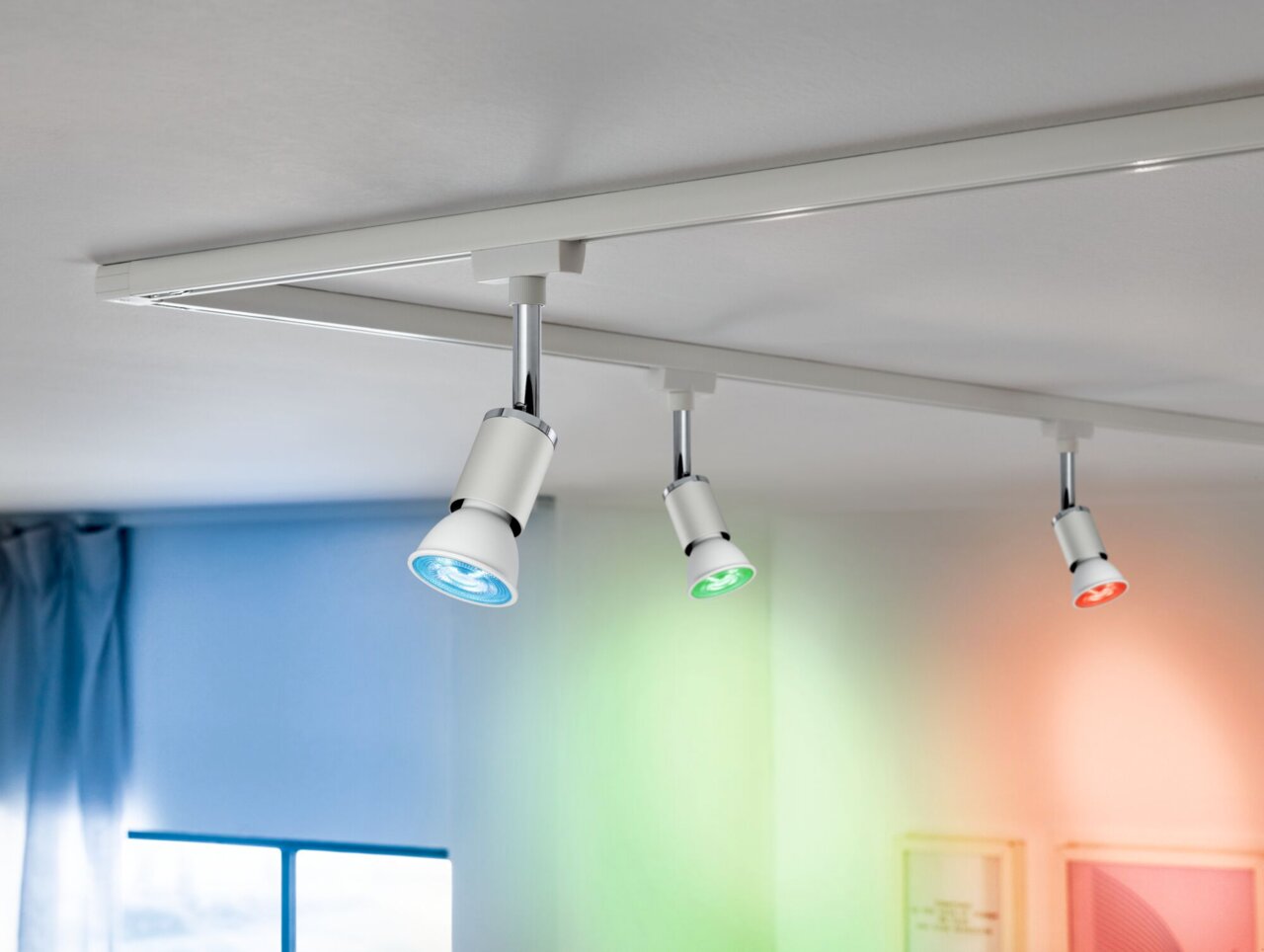 Dreifaches LED-Leuchtmittel von PAULMANN URAIL in einer Deckenmontage, mit blauer, grüner und roter Beleuchtung, seitliche Perspektive.