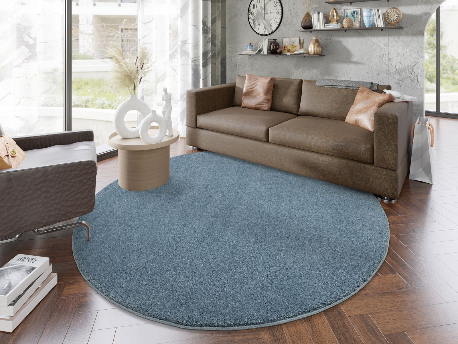 Runder, blauer Uni-Teppich in einem modernen Wohnzimmer mit braunem Sofa und Couchtisch, von oben betrachtet.