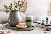 Ein stilvolles Longdrinkbecher-Set auf einem Tisch, umgeben von einer Vase mit Blumen, einem Schachbrett und einem Teller mit Keksen. Perspektive von vorne.