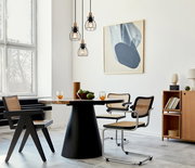 Moderne Hängeleuchte mit drei schwarzen Drahtkäfigen und Holzdetails, von der Decke hängend über einem Esstisch in einem stilvoll eingerichteten Raum, seitliche Perspektive.