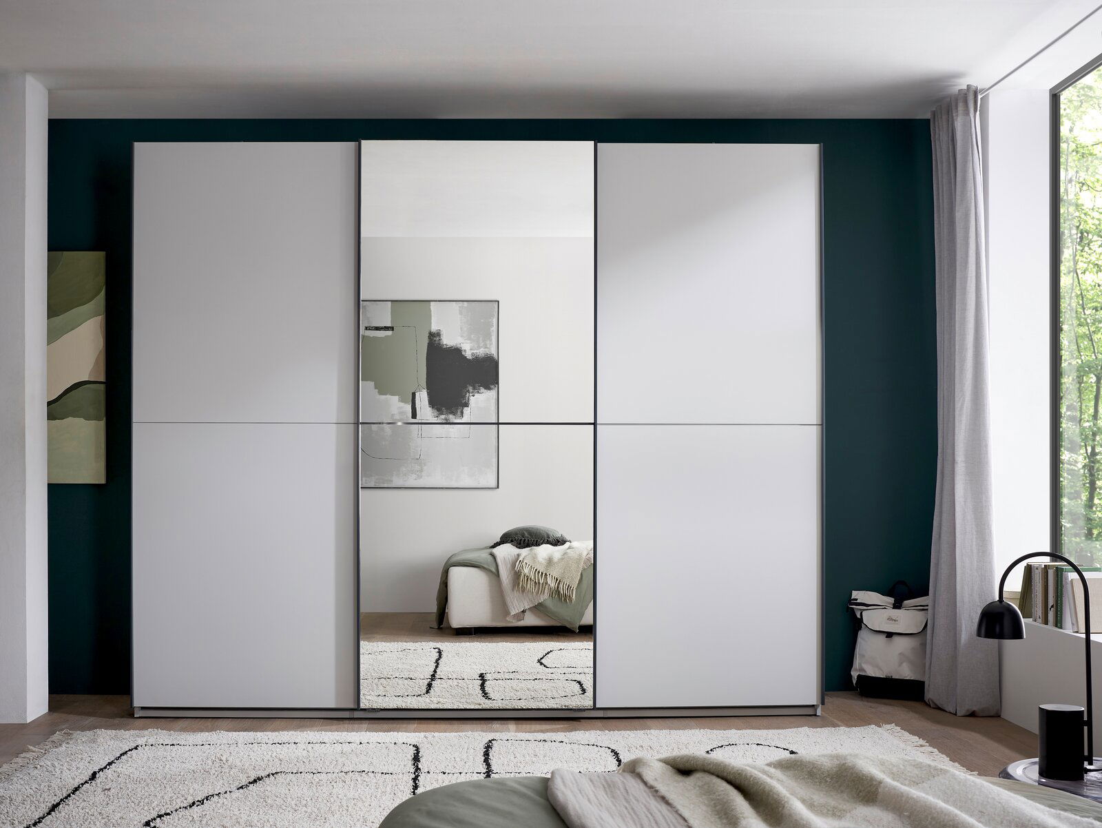 Moderner weißer Kleiderschrank mit drei Schiebetüren und mittlerer Spiegeltür im Schlafzimmer, Frontansicht auf Augenhöhe.