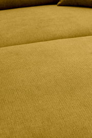 Nahaufnahme der Sitzfläche eines senfgelben Stoffsofas mit sichtbarer Webstruktur, aufgenommen aus leicht schräger Draufsicht.