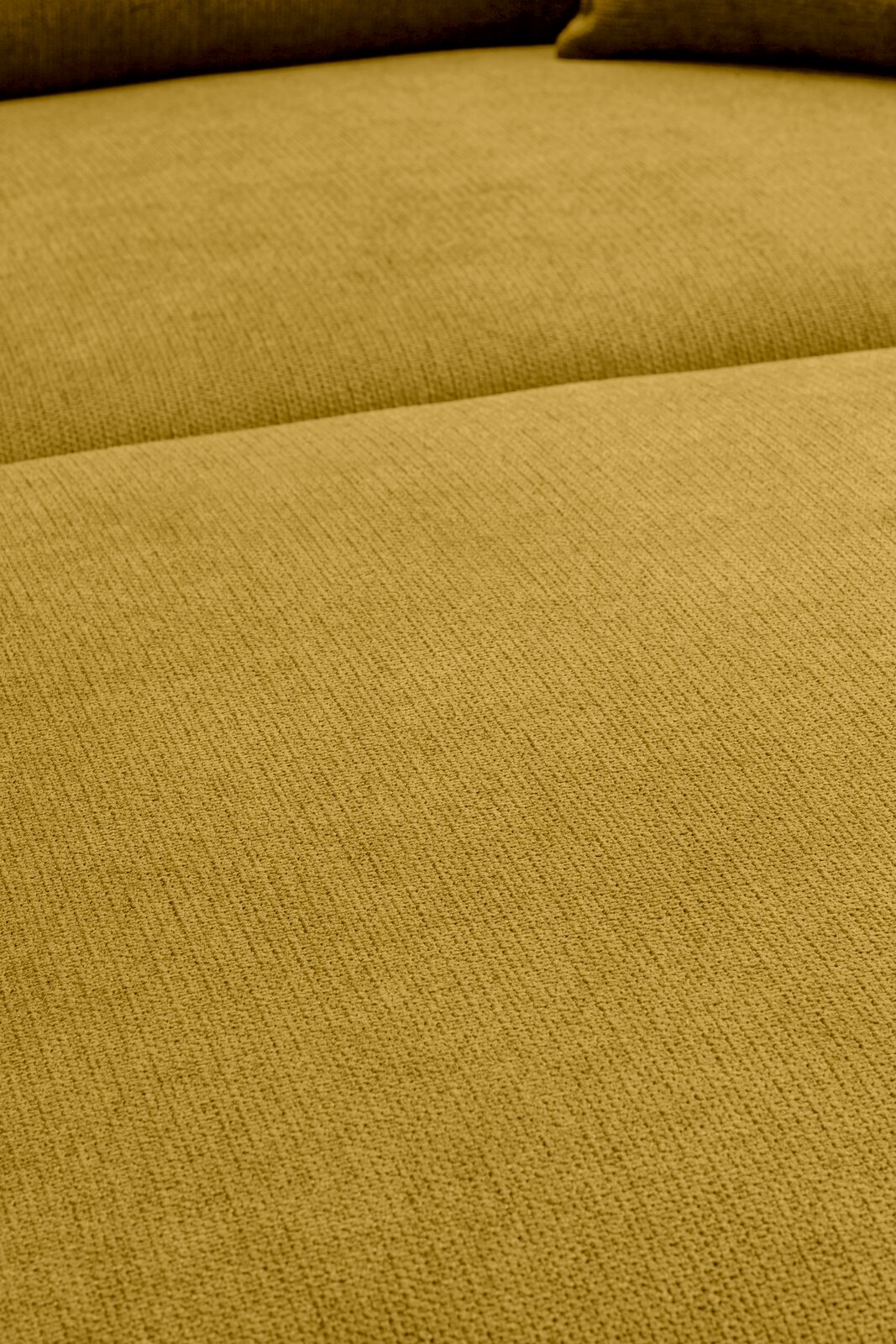 Nahaufnahme der Sitzfläche eines senfgelben Stoffsofas mit sichtbarer Webstruktur, aufgenommen aus leicht schräger Draufsicht.
