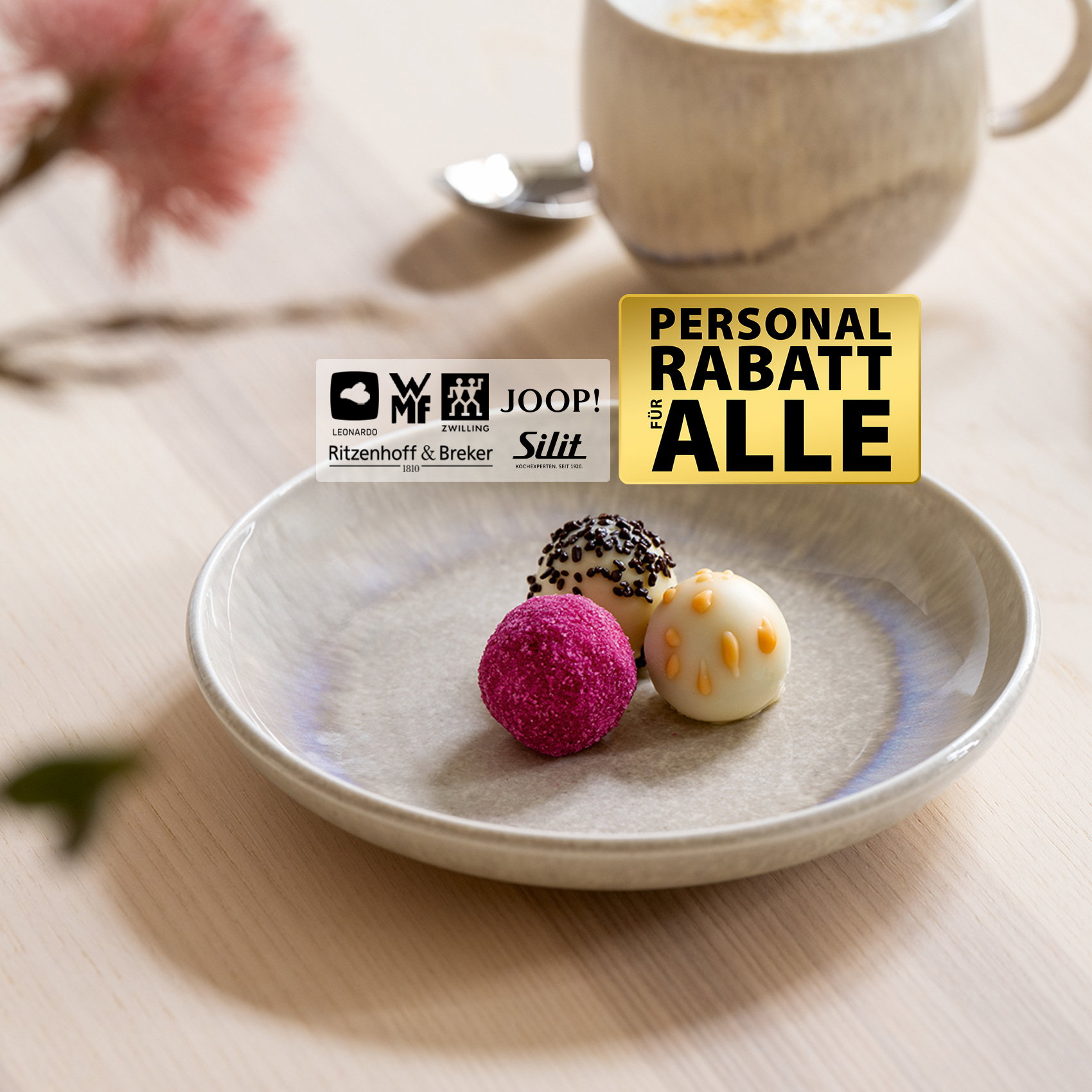 Drei bunte Pralinen auf einem eleganten Keramikteller, dazu eine Tasse Cappuccino.