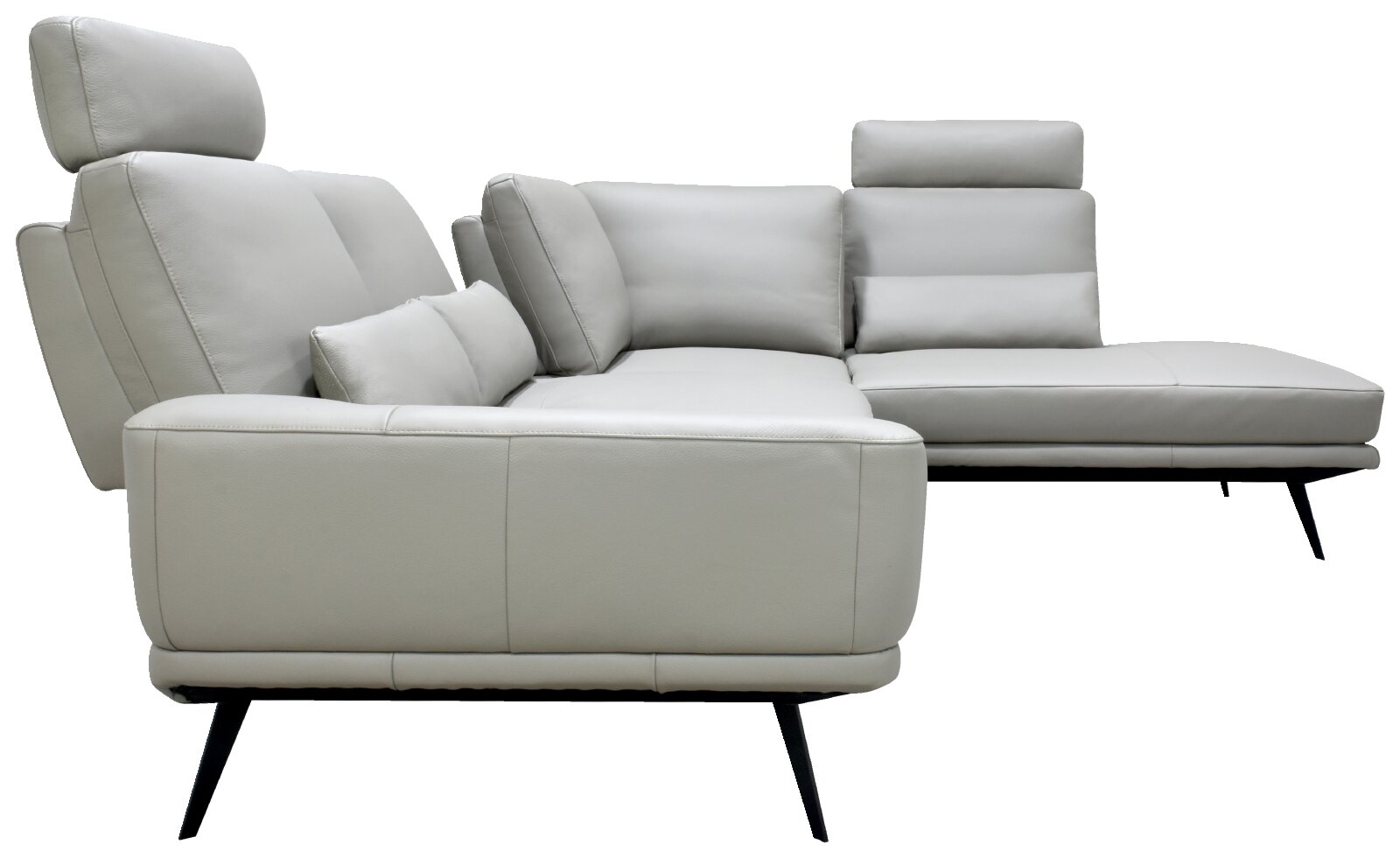 Moderne lichtgrijze leren hoekbank met chaise longue, verstelbare hoofdsteunen, sierkussens en slanke zwarte poten, gezien schuin van voren