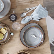 Speiseteller Lave 28cm beige in Vogelperspektive auf einem gedeckten Tisch mit Besteck und Serviette.