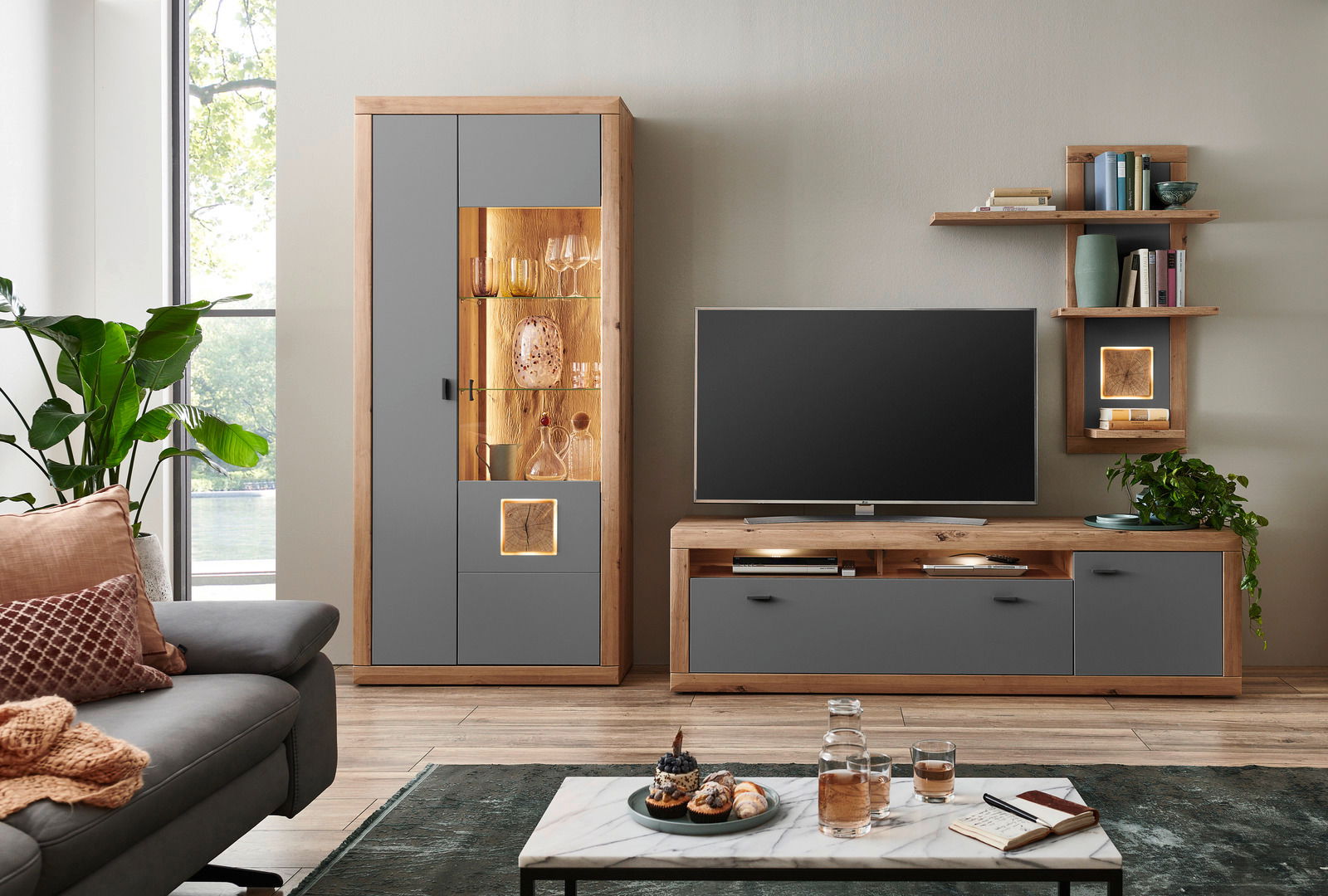 Moderne Wandkombination in Holzoptik mit grauen Fronten, bestehend aus Vitrine, TV-Board und Wandregal, frontal abgebildet.