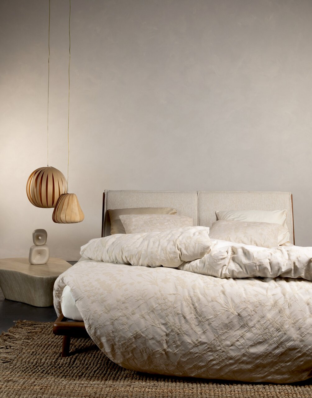Bett mit Essenza Home Bettwäsche MARIBEL in Cremefarben, seitliche Perspektive, mit hängenden Lampen und einem Beistelltisch im Hintergrund.