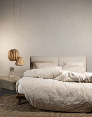 Bett mit Essenza Home Bettwäsche MARIBEL in Cremefarben, seitliche Perspektive, mit hängenden Lampen und einem Beistelltisch im Hintergrund.