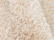 Nahaufnahme eines beigen Hochflor-Teppichs mit weicher, flauschiger Textur.
