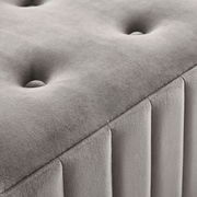 Nahaufnahme einer grauen Hockerbank mit gepolstertem, gestepptem Design und vertikalen Nähten, seitliche Perspektive