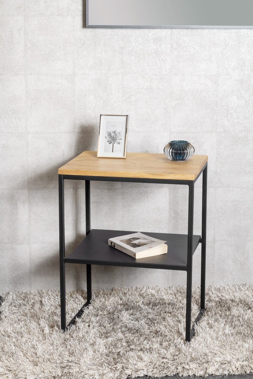 Beistelltisch mit Holzplatte und schwarzem Metallgestell, seitliche Perspektive, dekoriert mit einem Bilderrahmen, einer Vase und einem Buch auf einem Teppich.