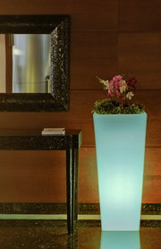 Hoher, leuchtender Blumentopf Melisa 50 mit Orchideen und Grünpflanzen, seitliche Perspektive.