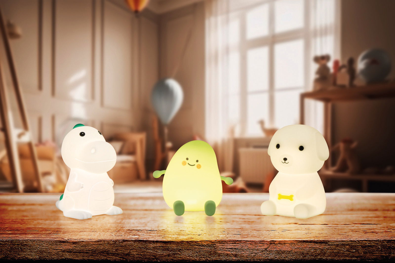 Drei Akku-Nachtleuchten in Form eines Dinosauriers, einer Avocado und eines Hundes auf einem Tisch in einem Kinderzimmer, frontal betrachtet.