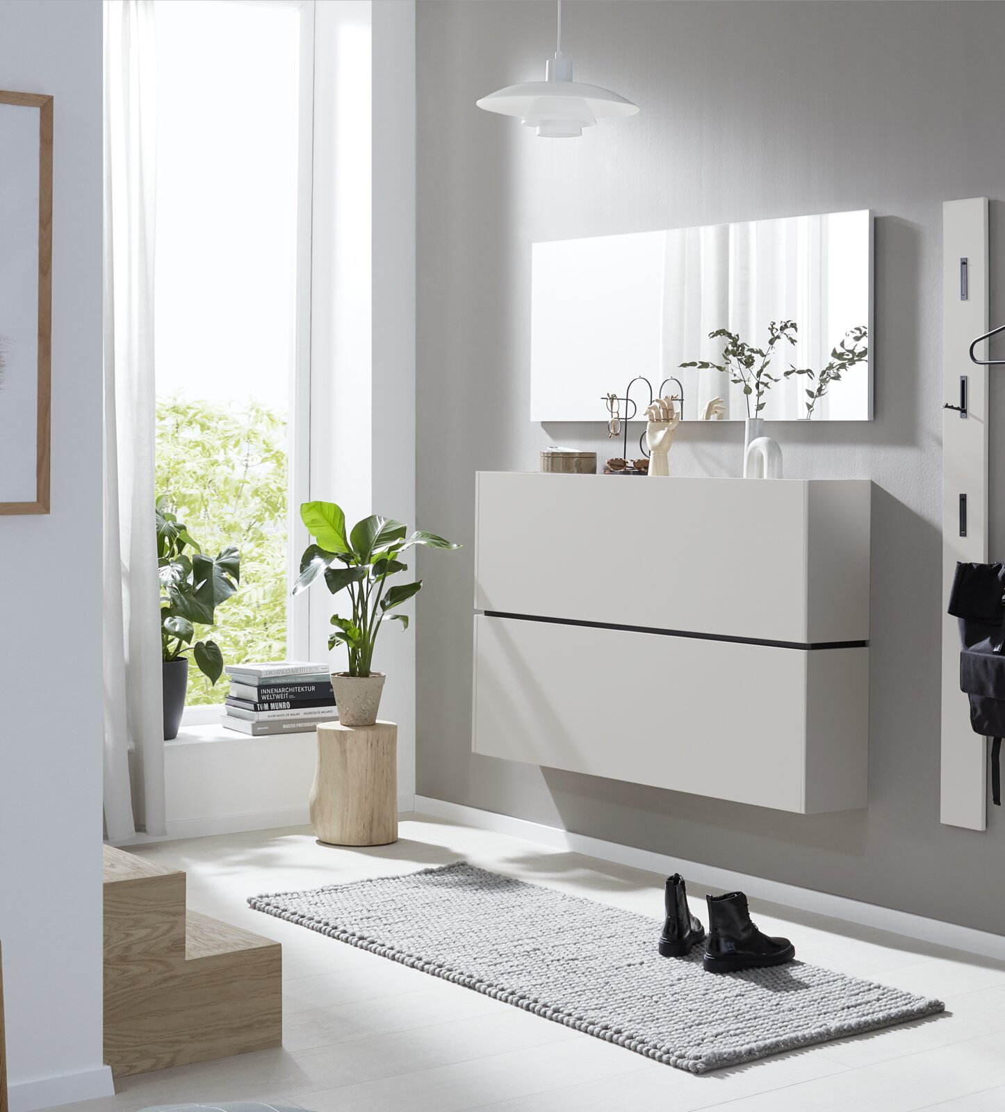 Wandhängender weißer Schuhschrank mit zwei grifflosen Klappen, aus leicht seitlicher Frontperspektive in einem hellen modernen Flur gezeigt.