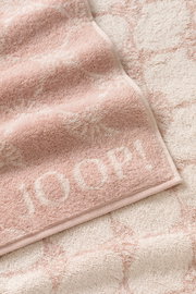 Nahaufnahme eines weichen, rosa Gästetuchs mit eingewebtem Muster und dem Schriftzug 'JOOP!' in der Ecke.