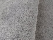 Nahaufnahme eines weichen, grauen Teppichs mit flauschiger Textur, seitliche Perspektive