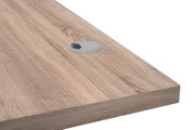 Nahaufnahme einer Schreibtischplatte aus Holz mit Kabeldurchlass, perspektivisch von der Seite aufgenommen.