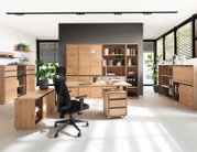 Moderne Büroumgebung mit einem Schreibtisch aus Holz in der Mitte, umgeben von passenden Aktenschränken und Regalen. Perspektive von vorne.