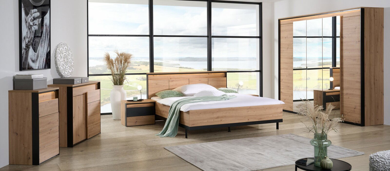 Voleo Bett Modernes Schlafzimmer mit einem großen Holzbett, flankiert von Nachttischen, in einem Raum mit großen Fenstern und Blick auf die Landschaft. Perspektive von vorne.