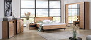 Modernes Schlafzimmer mit einem großen Holzbett, flankiert von Nachttischen, in einem Raum mit großen Fenstern und Blick auf die Landschaft. Perspektive von vorne.