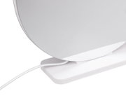 Detailansicht einer weißen, runden Tischlampe mit flachem Standfuß und sichtbarem Kabel, fotografiert aus seitlicher Nahperspektive