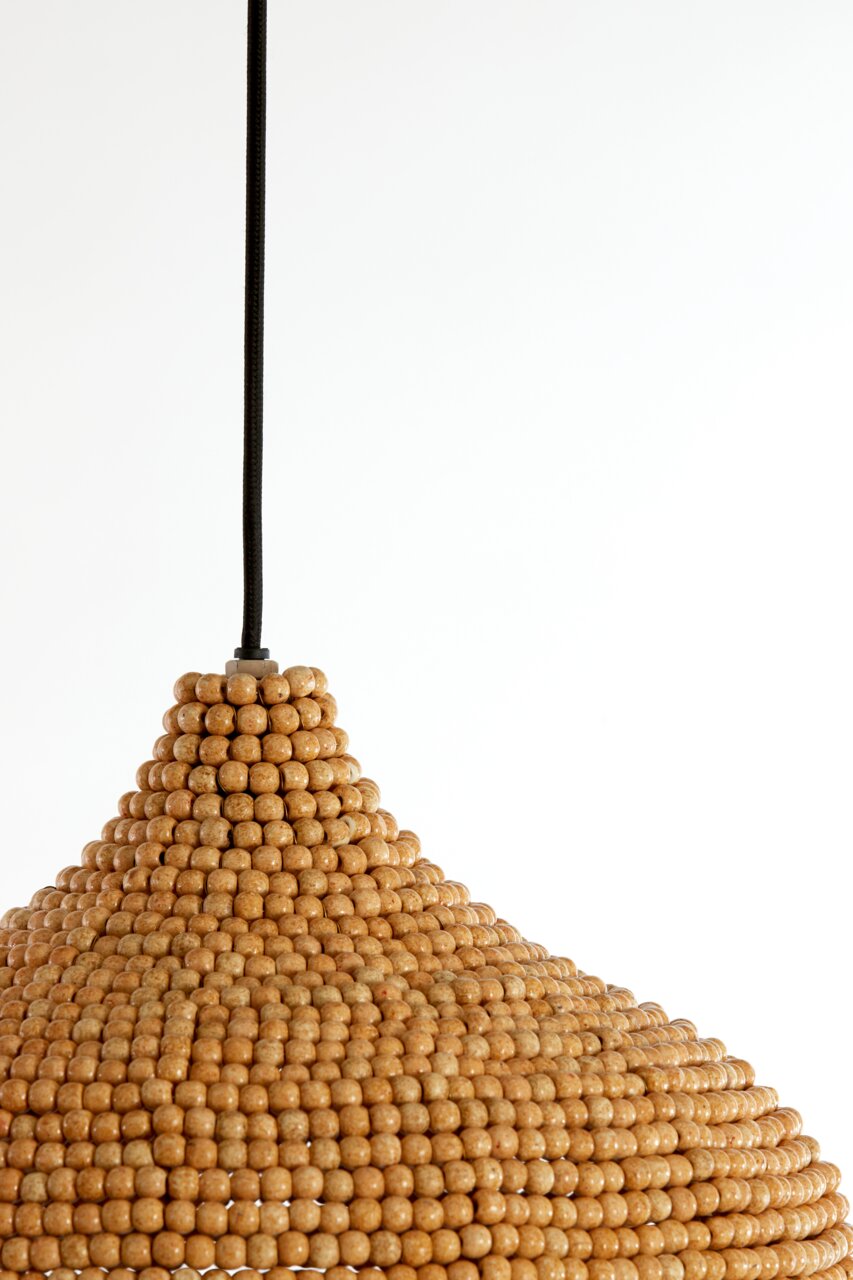 Nahaufnahme einer Hängeleuchte aus Holzperlen mit schwarzem Kabel, von der Seite betrachtet.