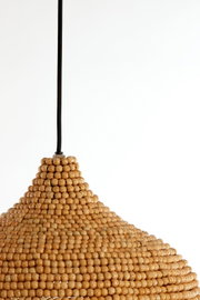 Close-up van een hanglamp van houten kralen met een zwarte kabel, gezien vanaf de zijkant.