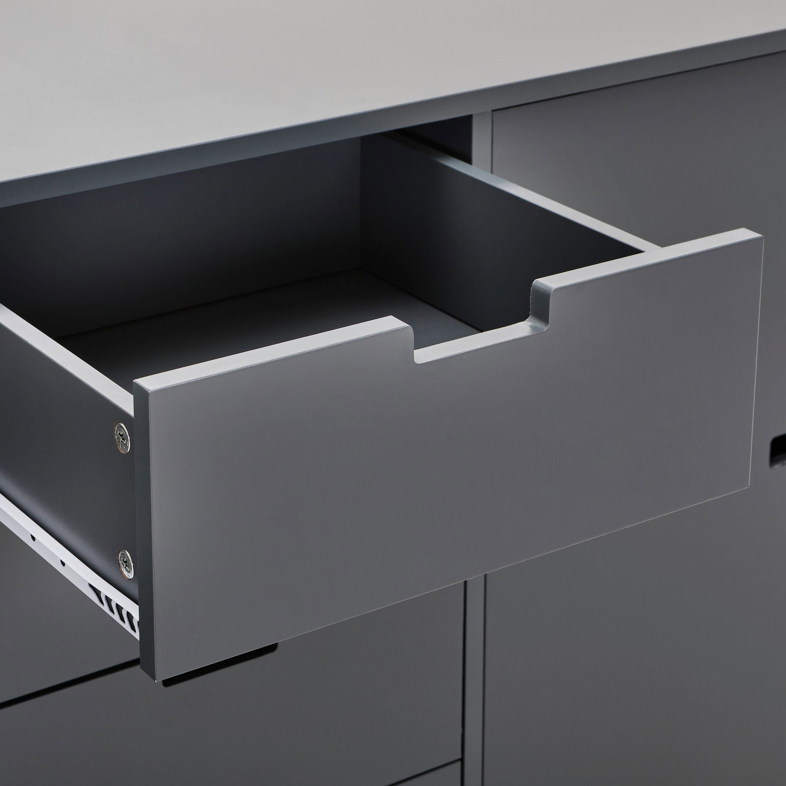 Nahaufnahme eines grauen Sideboards mit geöffneter Schublade, seitliche Perspektive