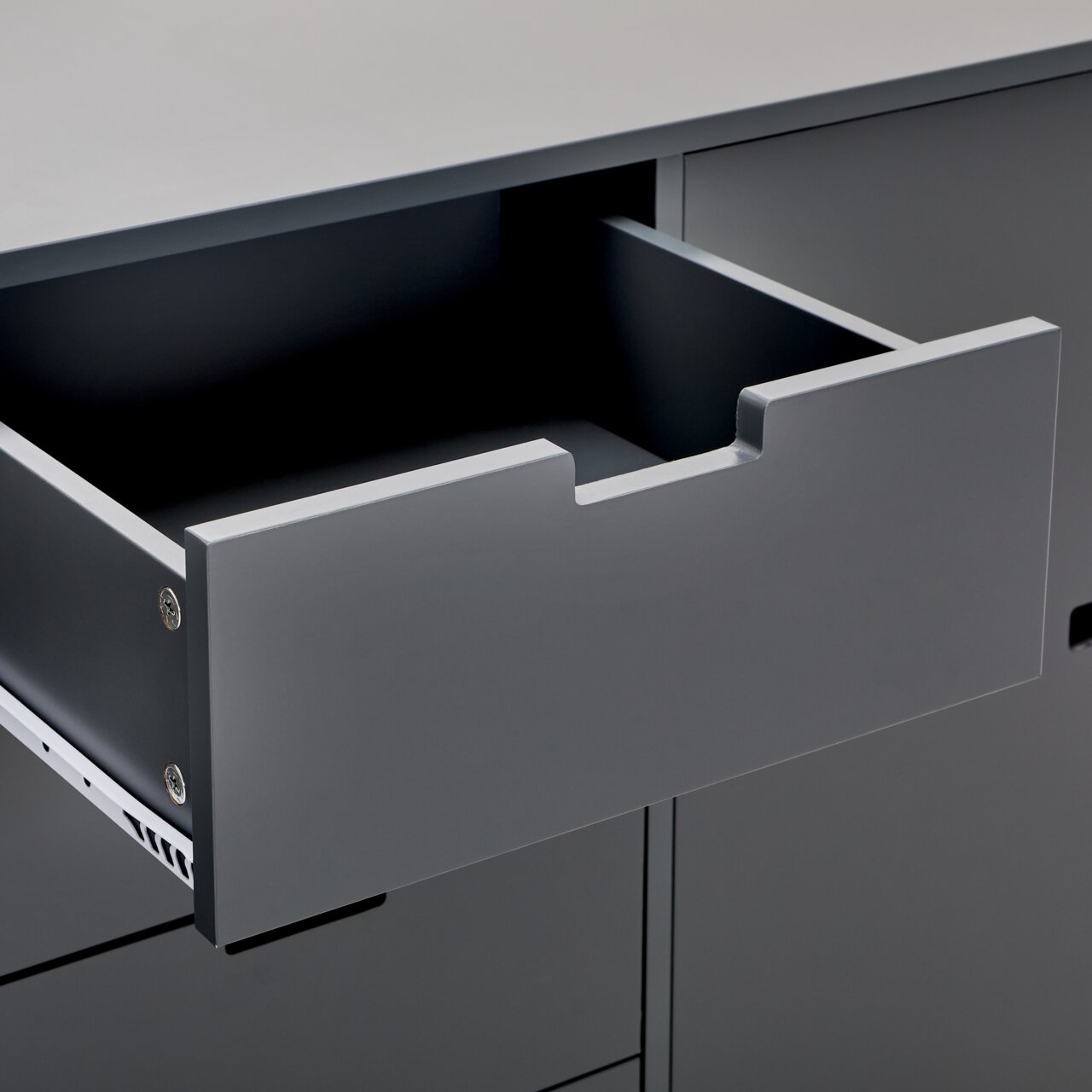 Nahaufnahme eines grauen Sideboards mit geöffneter Schublade, seitliche Perspektive