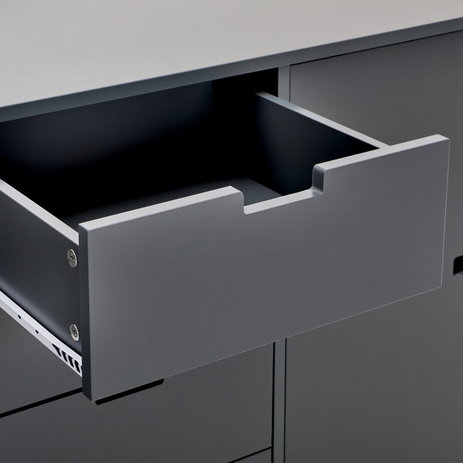 Nahaufnahme eines grauen Sideboards mit geöffneter Schublade, seitliche Perspektive