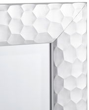 Nahaufnahme eines Spiegels mit facettiertem, sechseckigem Rahmen in silberner Optik, perspektivisch von der Ecke aus gesehen.