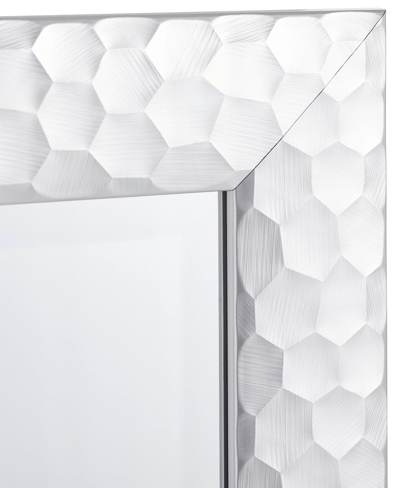 Nahaufnahme eines Spiegels mit facettiertem, sechseckigem Rahmen in silberner Optik, perspektivisch von der Ecke aus gesehen.