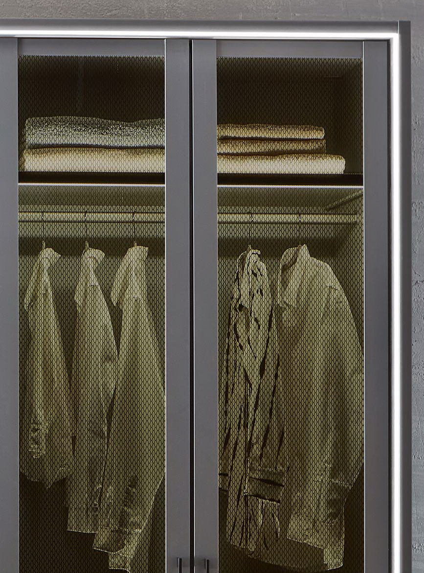 Nahaufnahme eines Drehtürenschranks mit sechs Türen, teilweise geöffnet, mit sichtbaren Regalen und hängender Kleidung.