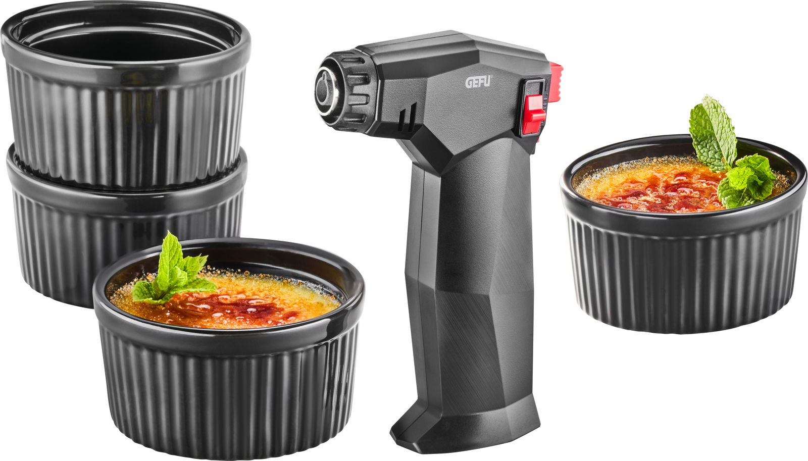 Crème Brûlée-Set mit einem Brenner und vier schwarzen Förmchen, zwei davon mit karamellisierter Oberfläche und Minzdekoration, seitliche Perspektive